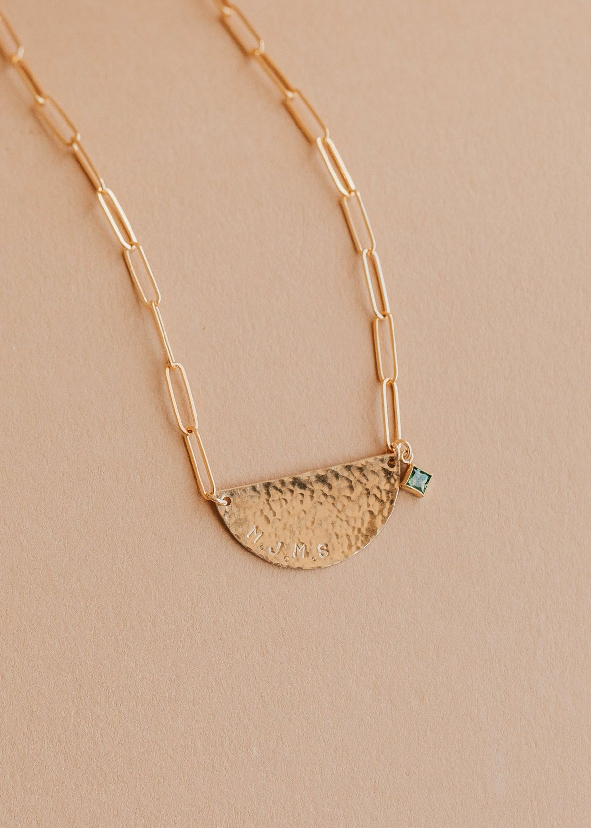 Gold necklace with a half-circle pendant on a beige background