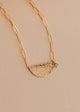 Gold necklace with a half-circle pendant on a beige background