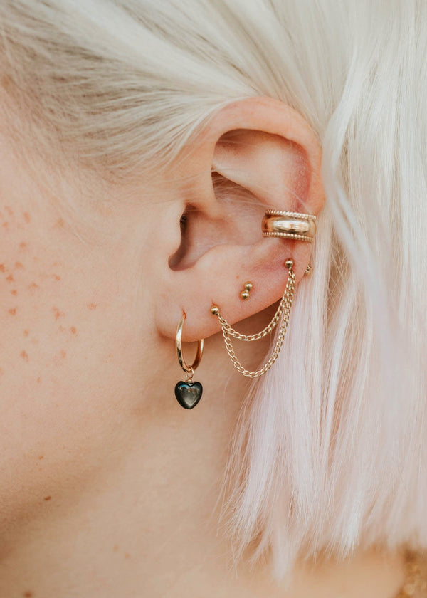 Close-up of an ear with multiple gold earrings and a heart-shaped earring.