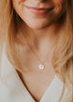 Close-up of a person wearing a delicate gold necklace with circular pendants.