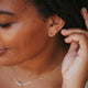 Fake double piercing earrings shown in double up post style by Hello Adorn styled with dainty chain bracelets and layering necklaces shown in 14k gold fill.