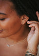 Fake double piercing earrings shown in double up post style by Hello Adorn styled with dainty chain bracelets and layering necklaces shown in 14k gold fill.