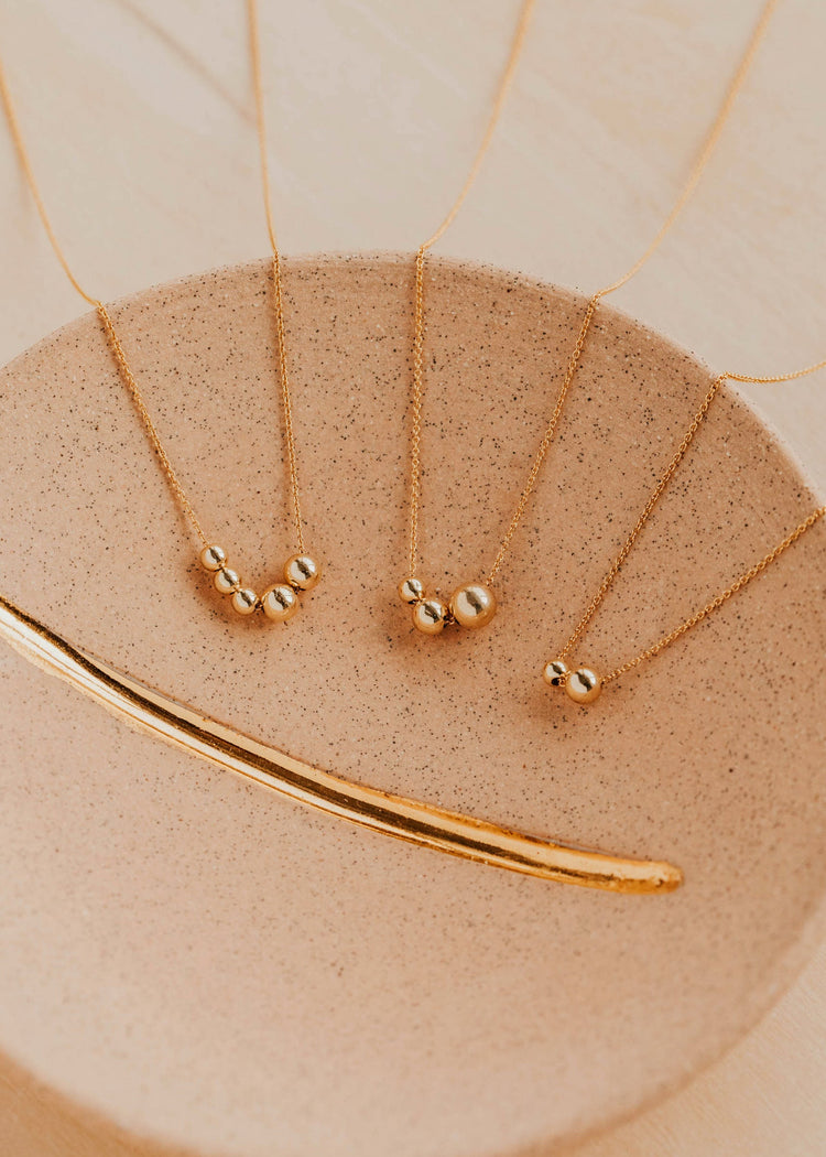 Gold necklaces on a beige surface