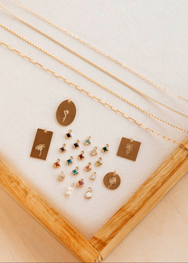 Collection of gold necklaces and pendants displayed on a white surface with a wooden frame.