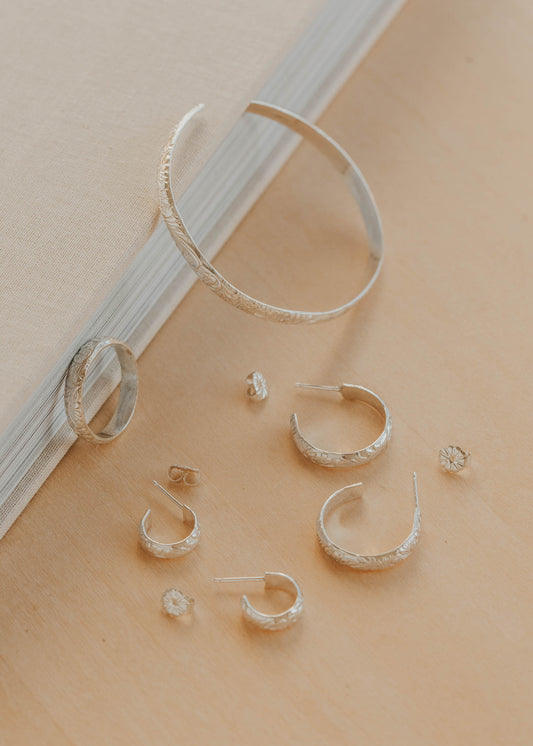 Silver hoop earrings on a beige surface