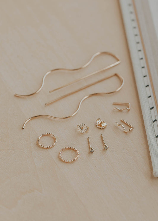 Set of gold jewelry pieces on a beige surface with a ruler for scale.