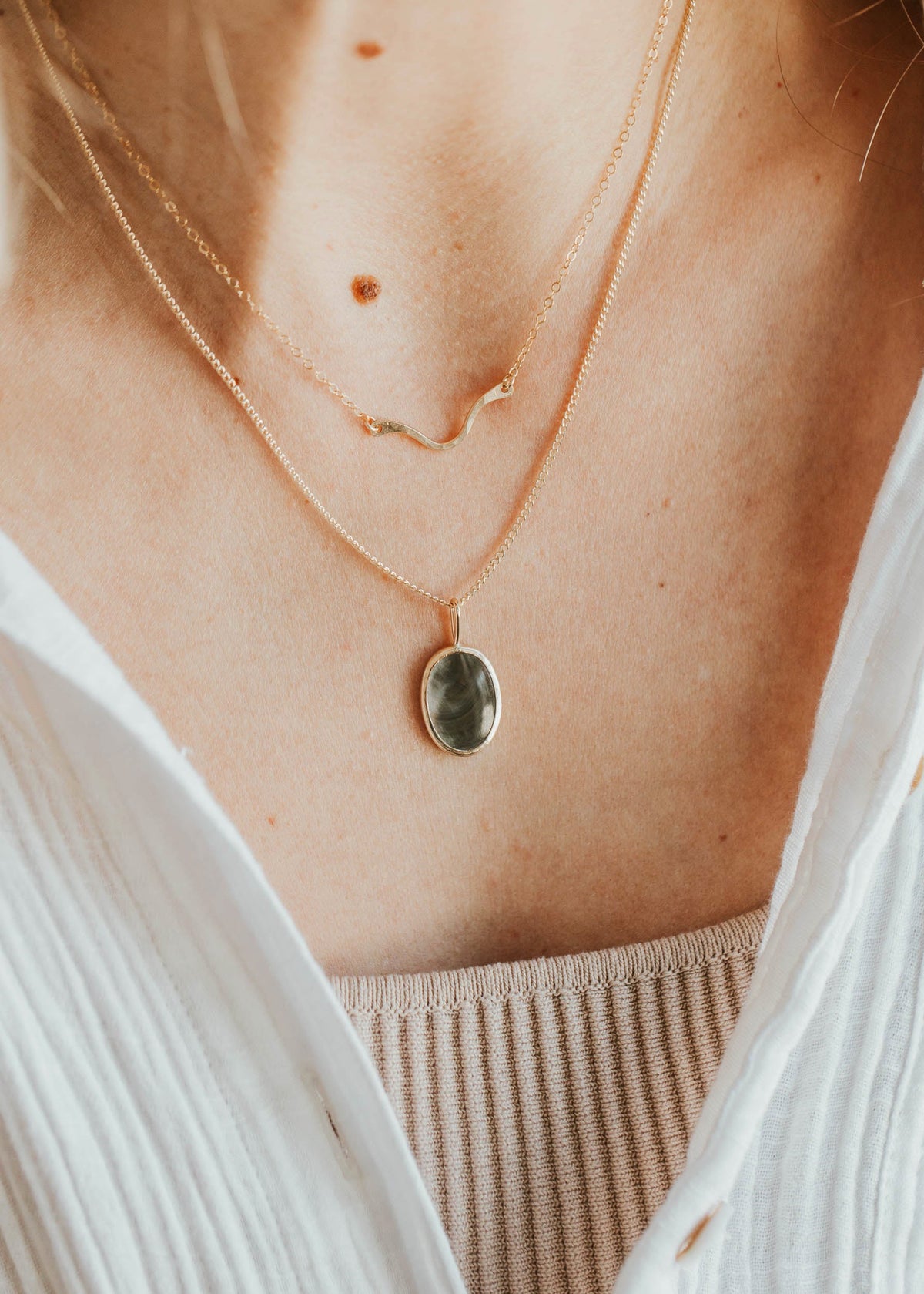 Close-up of a person wearing a delicate necklace with a small pendant.