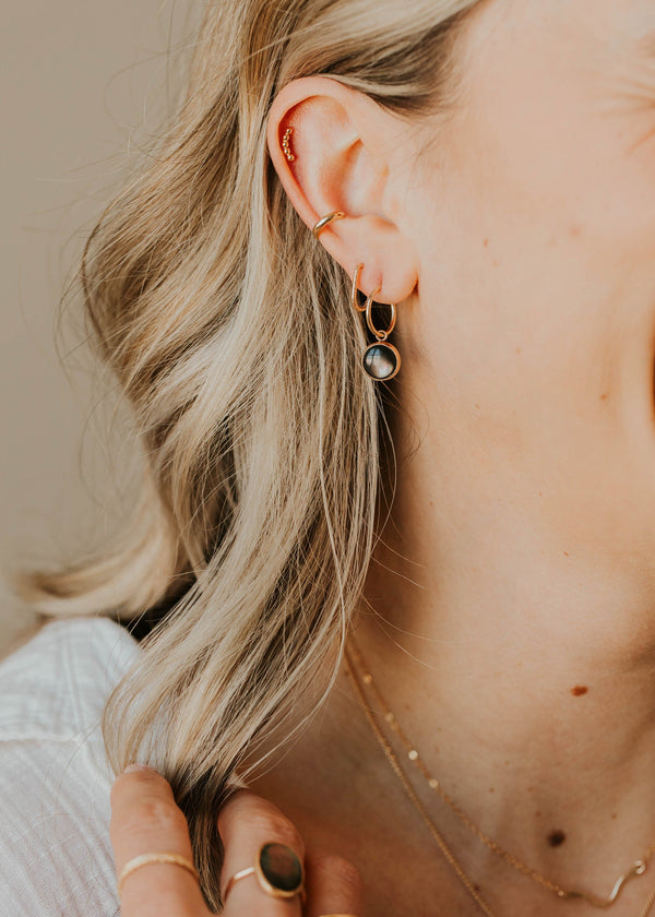 Close-up of a person wearing earrings and a necklace with a neutral background