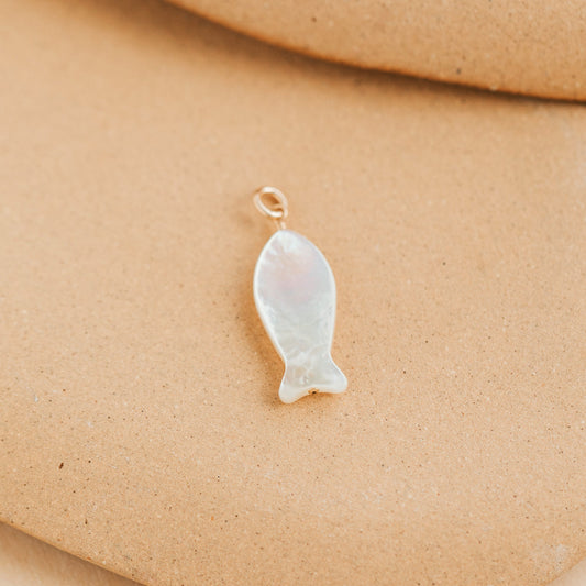 Fish-shaped pendant on a beige background