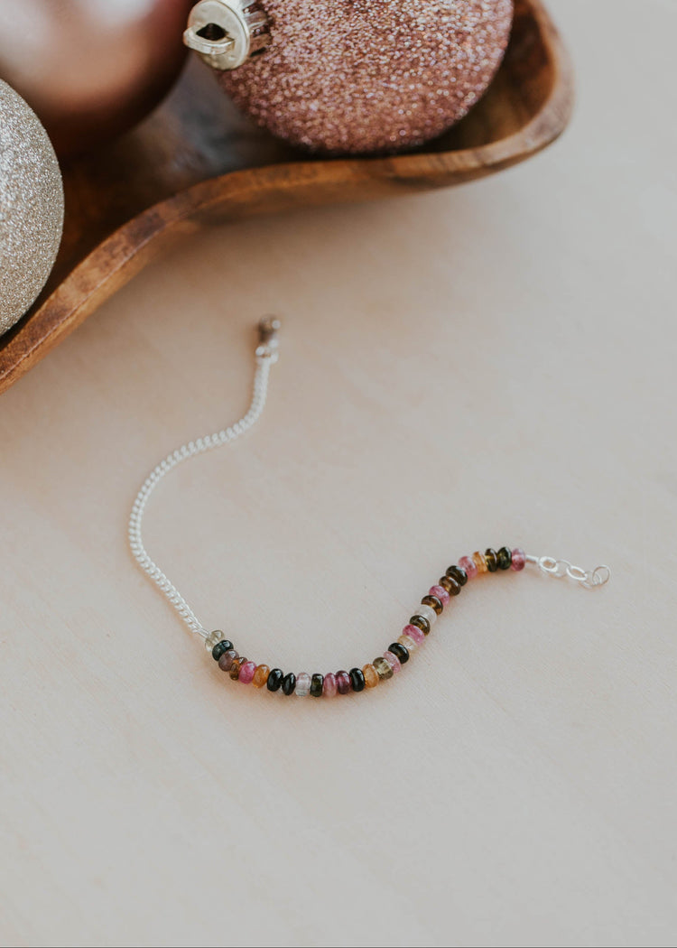 Beaded bracelet on a neutral surface with decorative items in the background