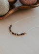 Beaded necklace on a neutral background with decorative items in the background