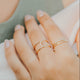 Close-up of a hand wearing two gold rings with a blurred background