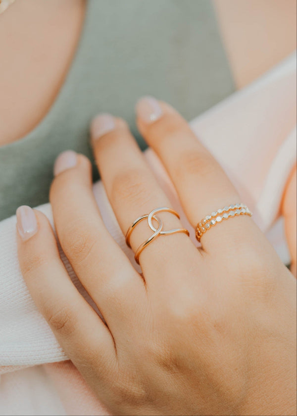 Close-up of a hand wearing two gold rings with a blurred background
