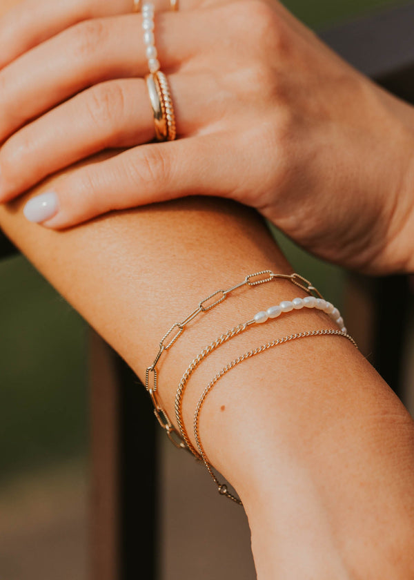 Close-up of a person's arm with multiple gold bracelets and rings.