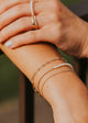 Close-up of a person's arm with multiple gold bracelets and rings.