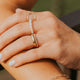 Close-up of a hand wearing multiple gold rings and bracelets against a blurred background