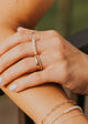 Close-up of a hand wearing multiple gold rings and bracelets against a blurred background