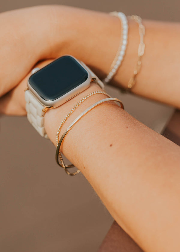 Person wearing a smartwatch with multiple bracelets on a blurred background