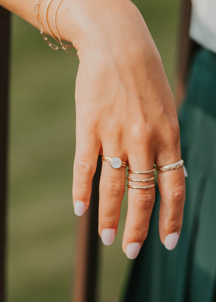 Close-up of a hand with multiple rings and bracelets against a blurred background
