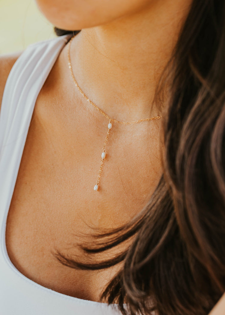 Close-up of a woman wearing a delicate necklace with small beads.