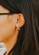 Close-up of an ear wearing gold hoop earrings with dark hair.