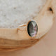 Gold ring with a green stone on a wooden surface