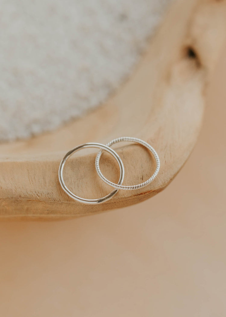 Two silver rings on a wooden surface with a neutral background