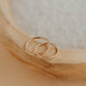 Two gold rings on a wooden surface with a soft focus background