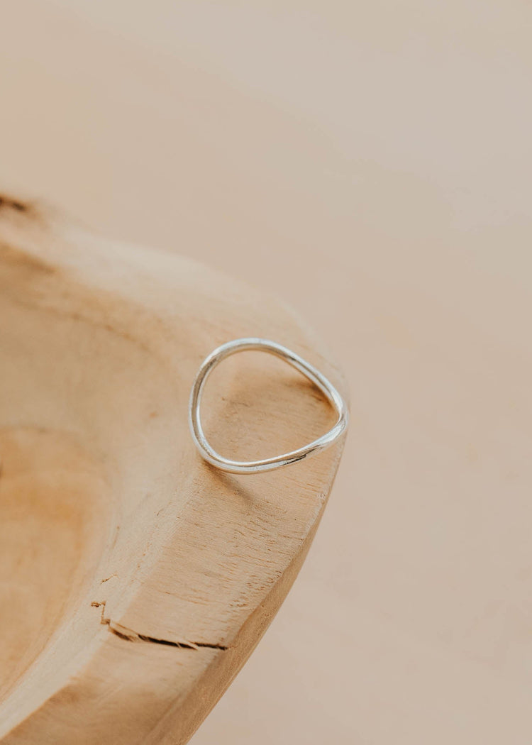 Silver ring on a wooden surface with a neutral background