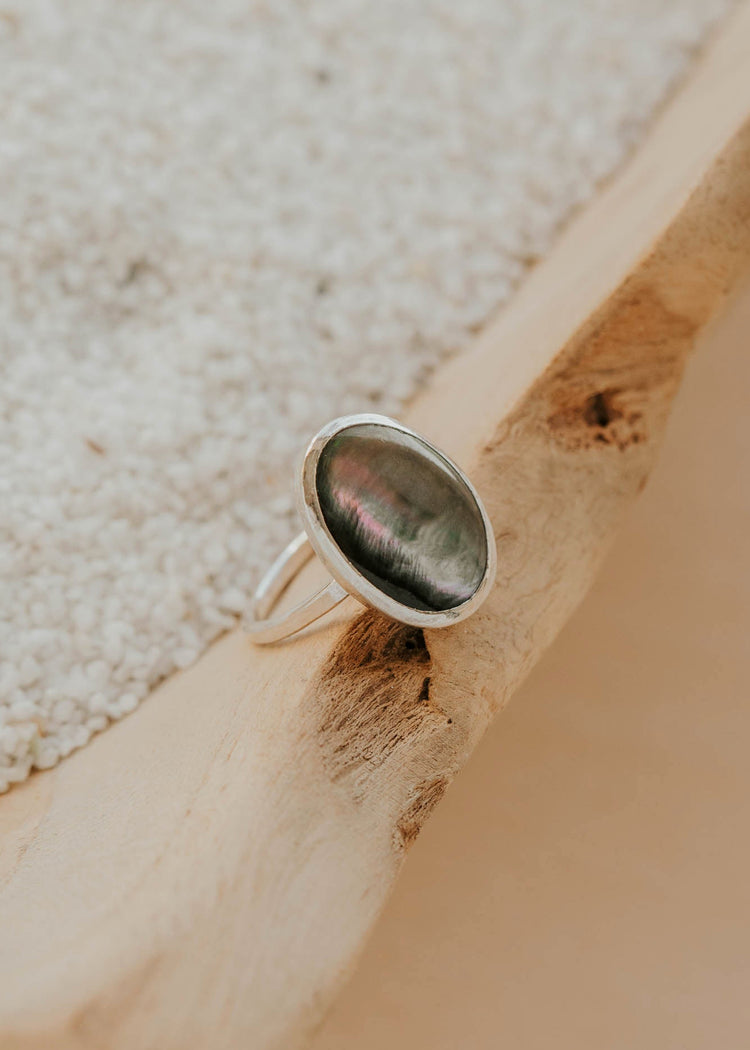 Silver ring with a green stone on a wooden surface