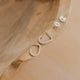 Silver earrings with 'J' design on a wooden surface