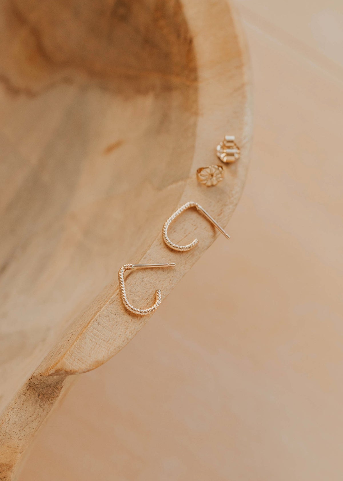 Gold earrings on a wooden surface