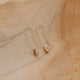 Gold earrings on a textured beige surface