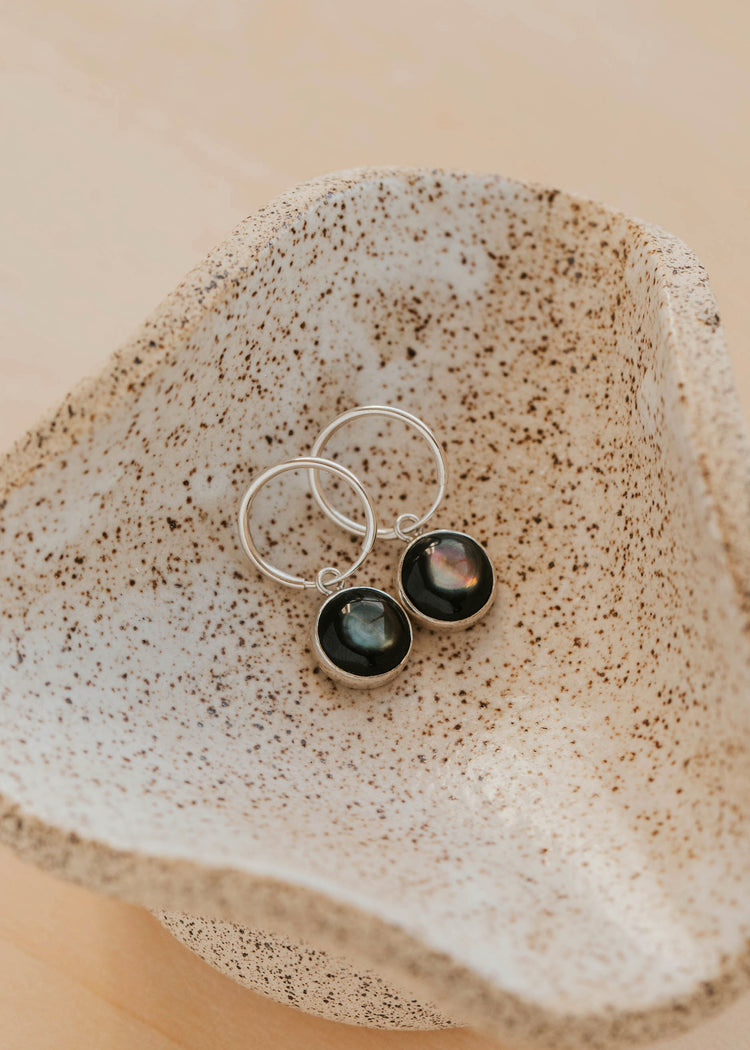 Silver earrings with gemstones on a textured stone surface