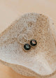 Silver earrings with gemstones on a textured stone surface
