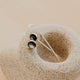 Silver earrings on a textured beige stone
