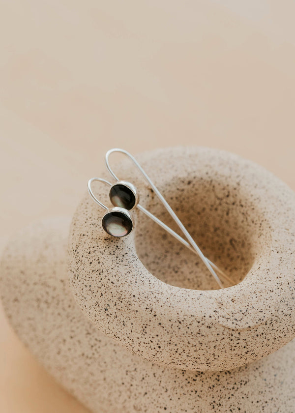 Silver earrings on a textured beige stone