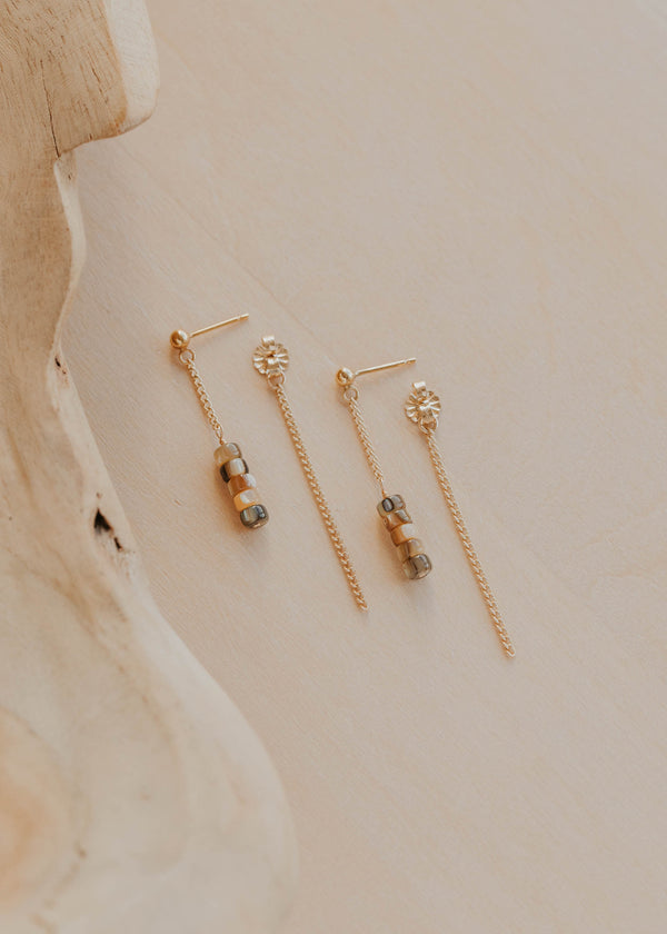 Pair of gold earrings on a neutral background