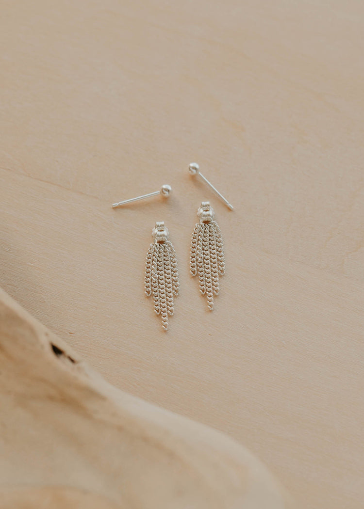 Pair of silver chain earrings on a beige surface