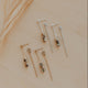 Set of gold earrings on a beige surface with dried grass