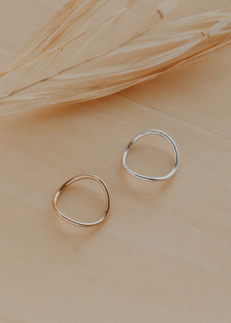 Two gold rings on a beige surface with dried grass.