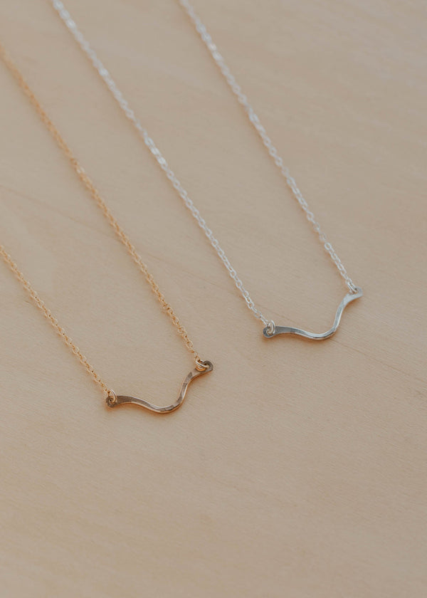 Two gold and silver necklaces on a beige background