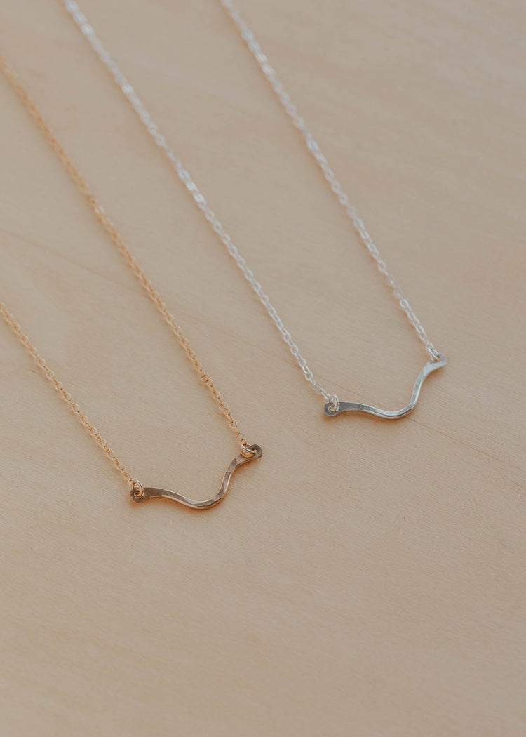 Two gold and silver necklaces on a beige background
