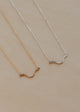 Two gold and silver necklaces on a beige background