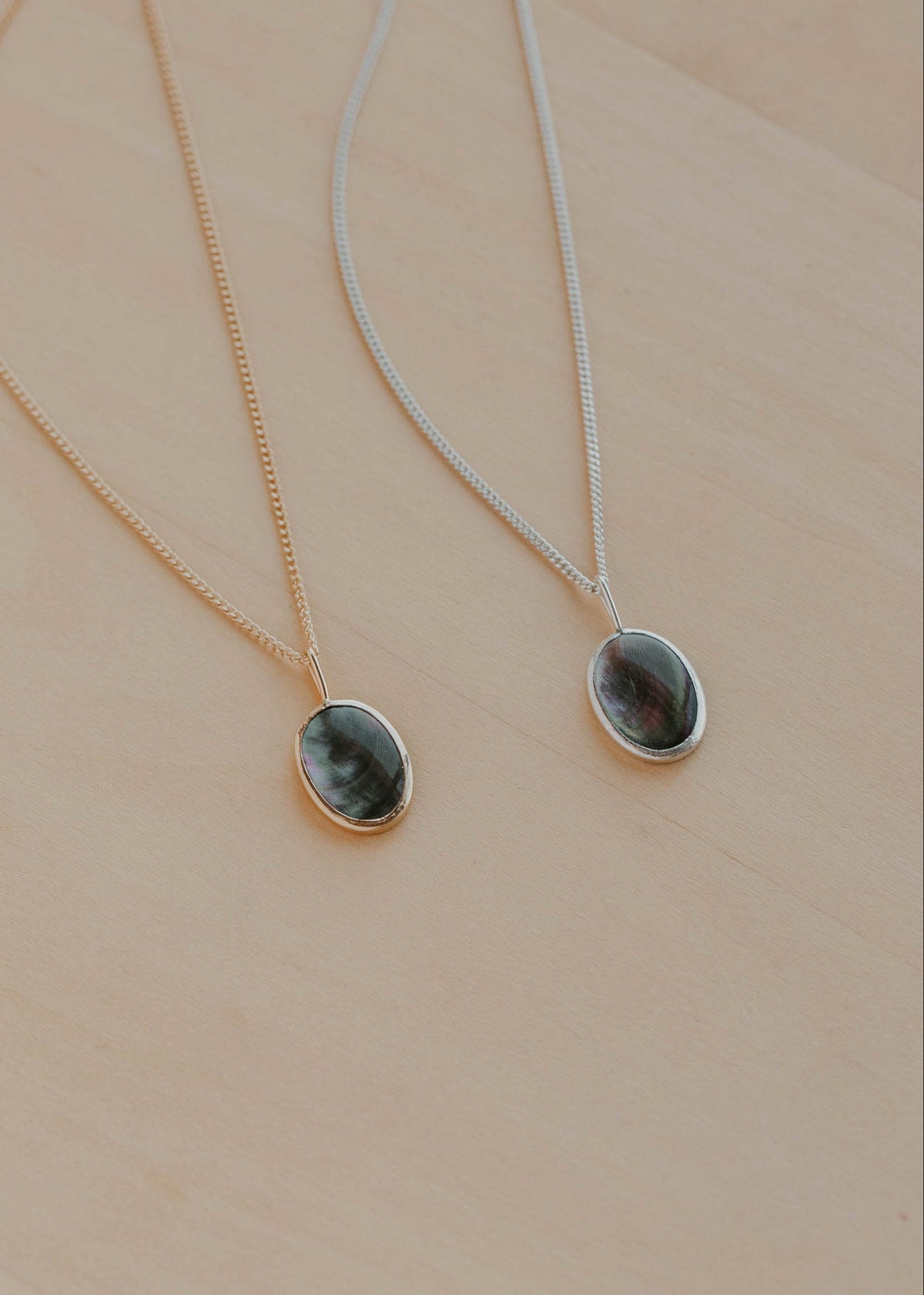 Two necklaces with pendant stones on a beige background