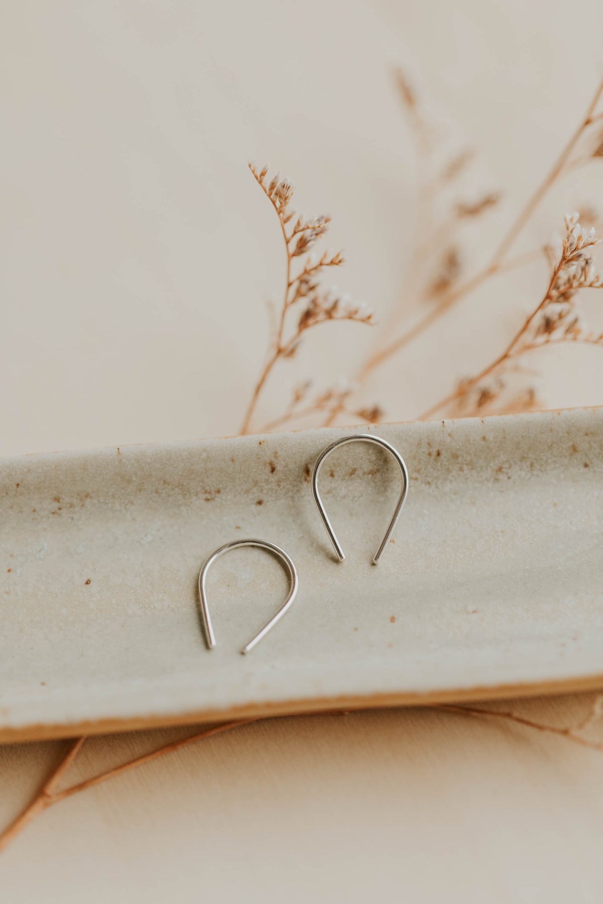 Sterling silver tiny horseshoe threader earrings by Hello Adorn on a ceramic dish
