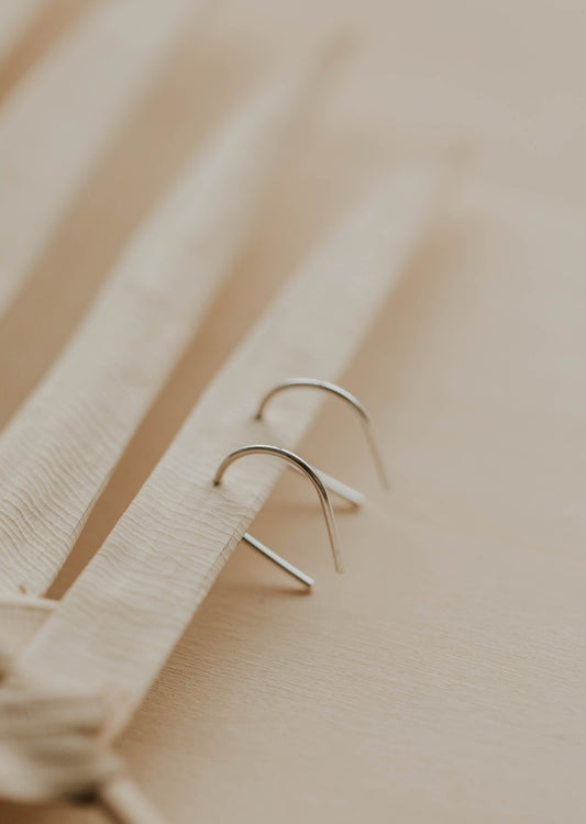 Sterling silver tiny horseshoe threader earrings by Hello Adorn on a wooden surface with neutral background