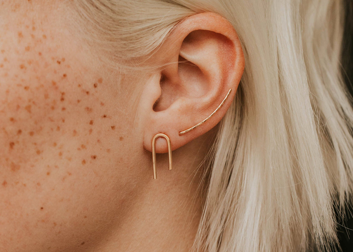 Close-up of a person wearing a gold ear cuff with blonde hair.