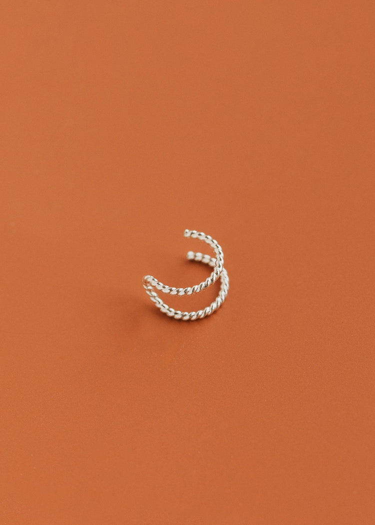 Silver nose ring cuff on a rust-colored background