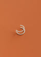Silver nose ring cuff on a rust-colored background